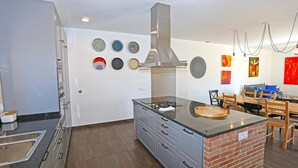 Cocina moderna con una isla central, gabinetes grises y una campana extractora de acero inoxidable.