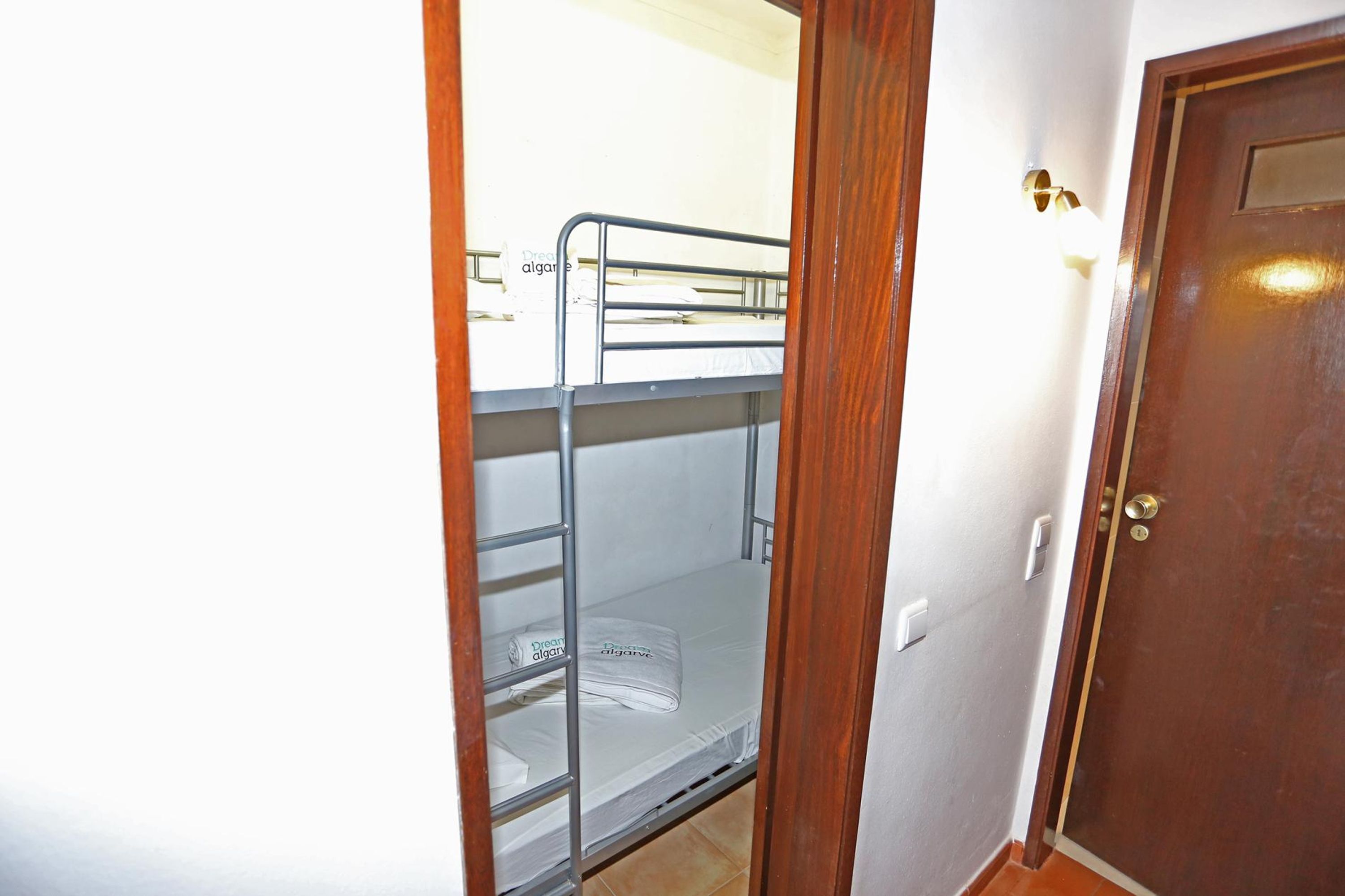 A bunk bed room with a wooden door and a light switch on the wall.