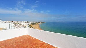 Un paisaje urbano costero con playa, edificios blancos y cielo azul despejado.