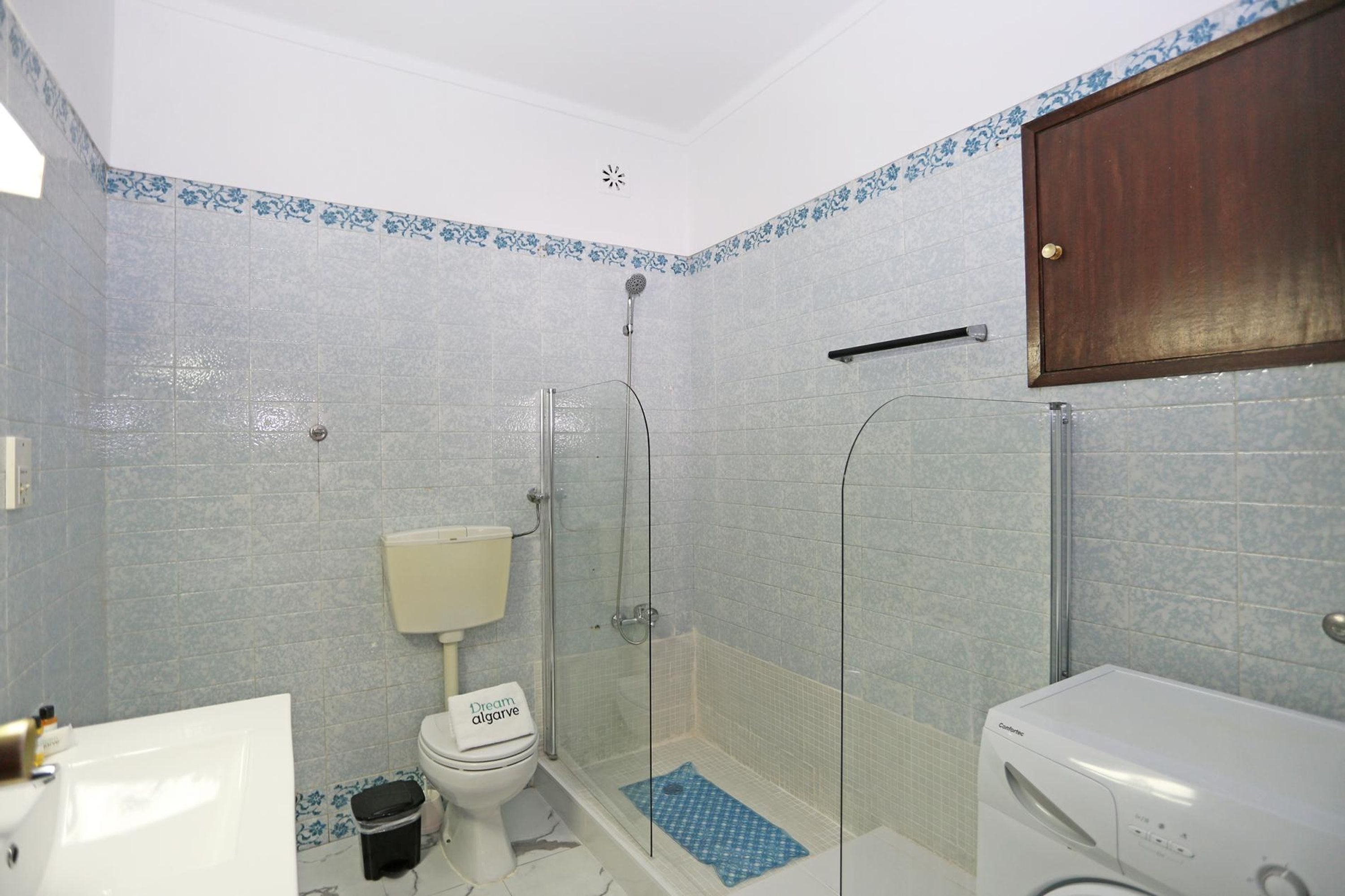 A bathroom with a toilet, shower, and a washing machine.