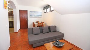 A compact living space with a grey sofa, a wooden coffee table, and a dining area with a table and chairs.