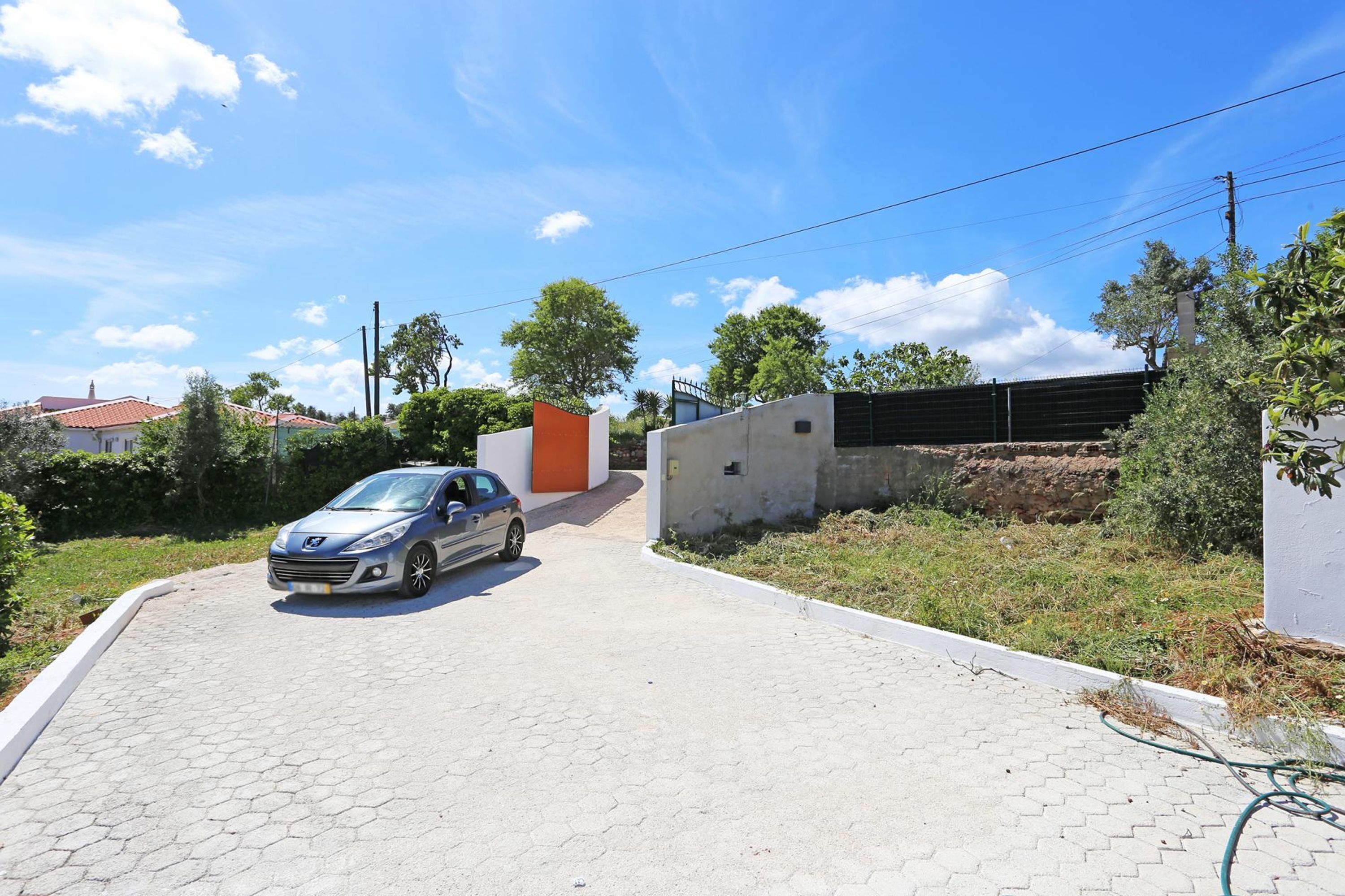 Une allée pavée mène à une maison moderne, avec une voiture garée sur le côté gauche.