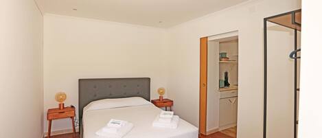 A hotel room with a bed, two bedside tables, a wardrobe, and a bathroom visible through an open door.
