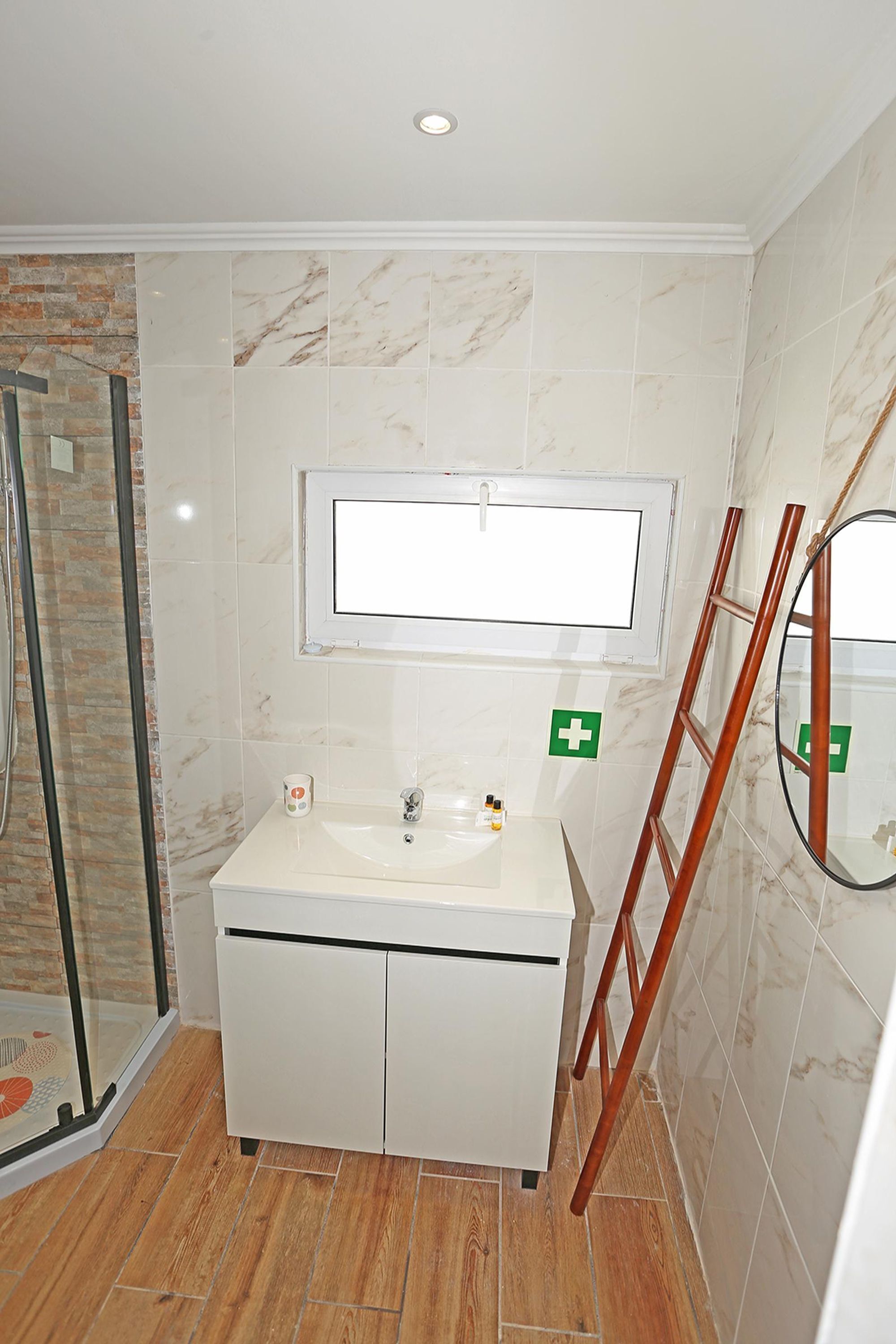 Une salle de bain avec un lavabo blanc, un miroir et un espace douche.