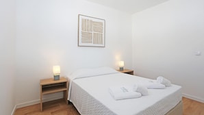 A neatly arranged hotel room with a bed, two bedside tables, and a wall-mounted artwork. - X 05 - 1 Bed Apartment in Quinta da Ponte (Lagos)