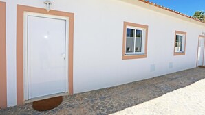 Un edificio con una hilera de puertas y ventanas, un techo de tejas y un suelo adoquinado de piedra.