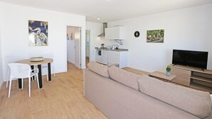 A modern apartment with a dining area, kitchenette, living room, and a TV. - X 06 - 1 Bed Apartment in Quinta da Ponte (Lagos)