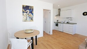A modern kitchen with white cabinets, a built-in oven, and a microwave. - X 06 - 1 Bed Apartment in Quinta da Ponte (Lagos)