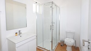 A modern bathroom with a glass shower enclosure, a white sink with a mirror above it, and a toilet. - X 10 - 2 Bed Apartment in Quinta da Ponte (Lagos)