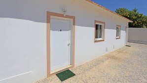 A building with three doors, each with a window above. The building has a tiled roof and a paved ground. - X 04 - 1 Bed Apartment in Quinta da Ponte (Lagos)