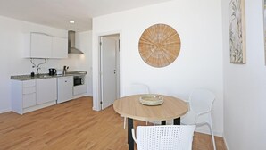 Een moderne keuken met witte kasten, een ronde houten tafel en twee witte stoelen.