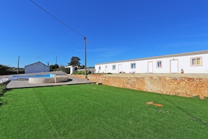 A white building with a stone wall and a swimming pool.