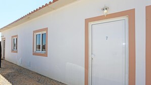 Een gebouw met een witte gevel, kamer nummer 7, en een geplaveid pad.