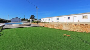 A white building with a stone wall and a swimming pool. - X 09 - 1 Bed Apartment in Quinta da Ponte (Lagos)