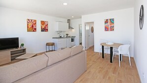 A modern apartment with a living room, kitchenette, dining area, and a TV on a wooden stand. - X 09 - 1 Bed Apartment in Quinta da Ponte (Lagos)