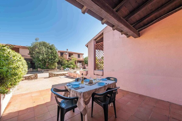 An outdoor patio with a table set for dining, surrounded by stone walls and greenery.