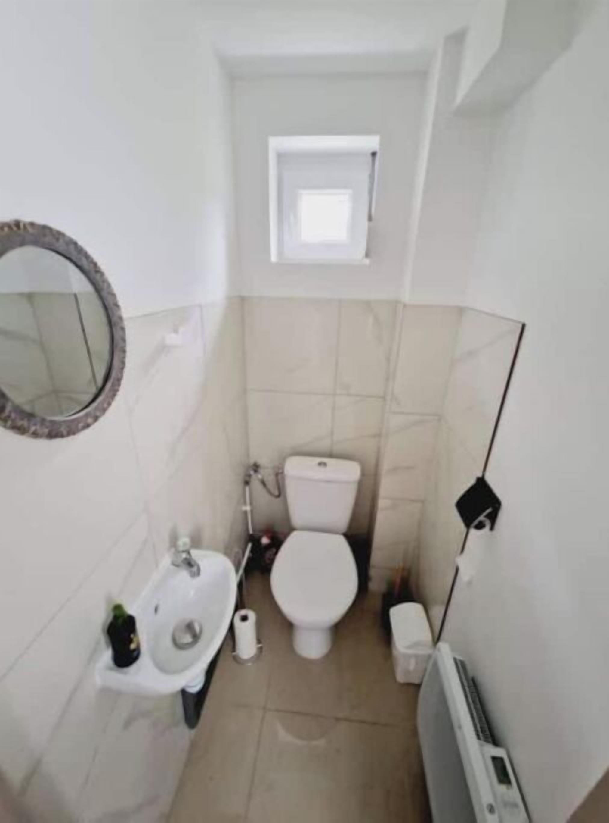 Une petite salle de bain compacte, équipée de toilettes, d’un lavabo et d’un miroir.