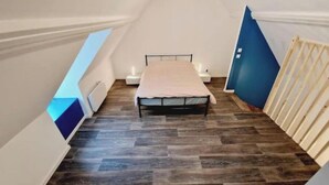 A small, narrow room with a bed, a nightstand, and a window. - Quiet, fully-equipped house with garden (Maing)