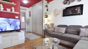 Un salon comprenant un téléviseur, un canapé, une table basse en verre et des objets de décoration.