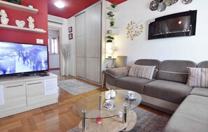 Een woonkamer met een televisie, bank, glazen salontafel en decoratieve accessoires.