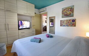 Een hotelkamer met een bed, een televisie op een dressoir, een kledingkast en twee decoratieve wandpanelen.