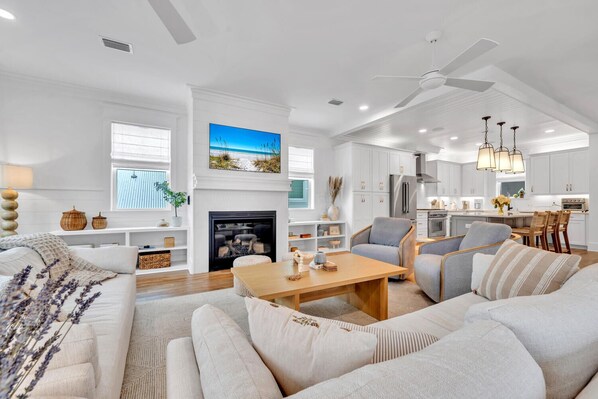 A spacious living room with a fireplace, a dining area, and a kitchen.