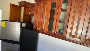 A kitchen with wooden cabinets, a black refrigerator, and a stainless steel oven.