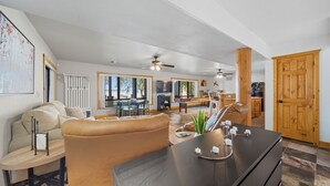 A spacious living room with a large sofa, a dining area, and a kitchen visible in the background. - Lakefront Luxury Log Cabin on Grand Lake O’ the Cherokees (Jay)