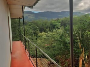 Un balcón con vista a un paisaje verde exuberante y montañas distantes.