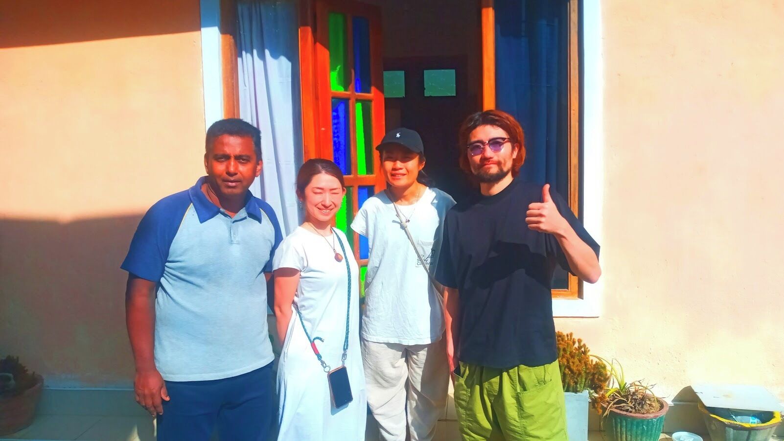 Un groupe de personnes se tient devant un bâtiment qui possède une fenêtre et une porte.