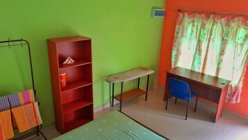 Une pièce comprenant un lit, un bureau, une chaise, une bibliothèque et une fenêtre avec des rideaux.