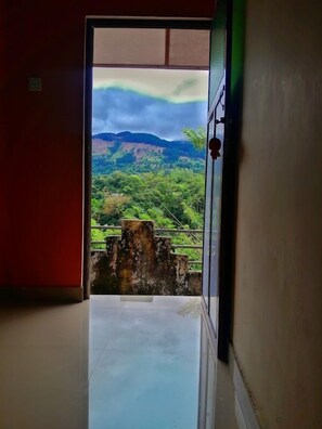 A corridor leading to a balcony with a view of a green landscape and mountains. - Galkotuwa Estate (Kandy)