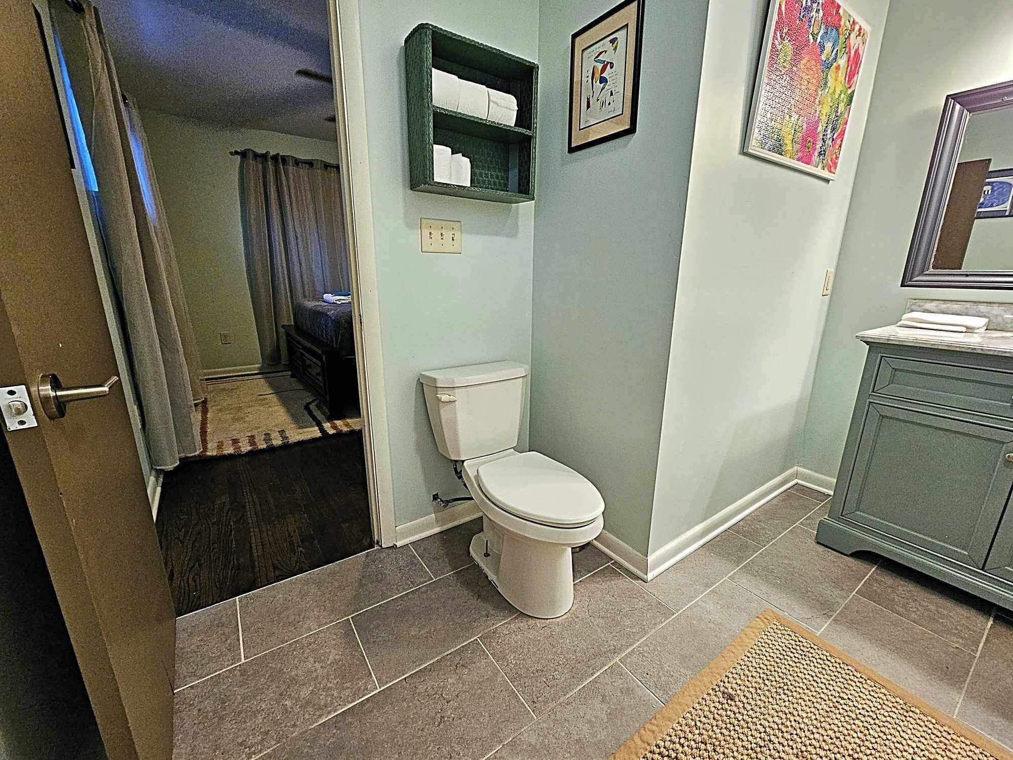 Et badeværelse med toilet, vask og bruseområde.