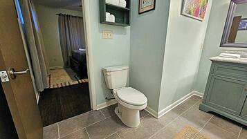 Et badeværelse med toilet, vask og bruseområde.