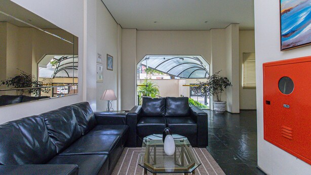 A modern lobby with a black leather sofa, a glass coffee table, and a red locker. - Studio With Balcony Sp-an606 (São Paulo)