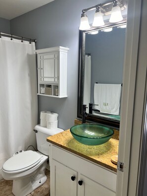 A bathroom with a toilet, a green glass sink, a mirror, and a towel hanging on the wall. - Cozy 2-bedroom Townhome with free parking in charming Downtown Chattanooga (Chattanooga)
