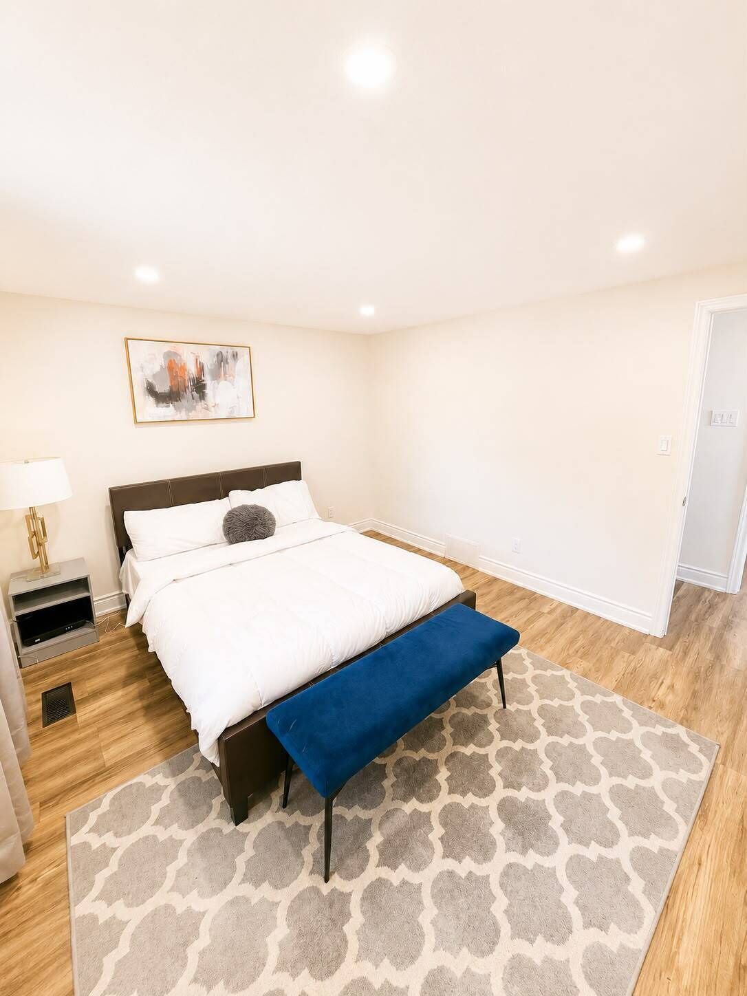 Une chambre à coucher avec un lit, une table de chevet, une lampe et un tapis.