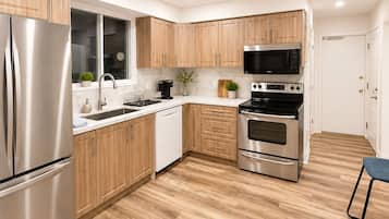 Une cuisine moderne avec des meubles en bois, des appareils électroménagers en acier inoxydable et un pare-feu en marbre.