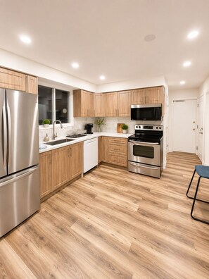 A modern kitchen with wooden cabinets, stainless steel appliances, and a marble backsplash.
