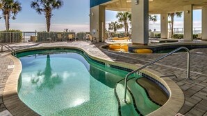 Un espace piscine offrant une vue dégagée sur l’océan, avec des chaises longues et des palmiers.