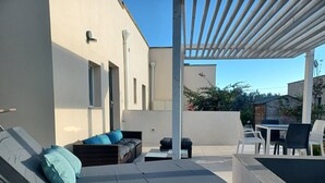 Eine moderne Außenveranda mit einer Couch, einem Tisch und Stühlen.