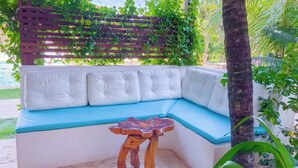 A covered outdoor seating area with a cushioned bench and a wooden table. - Charming bungalow in garden with lot of privacy - in an exclusive condo. (Guajiru Trairi)