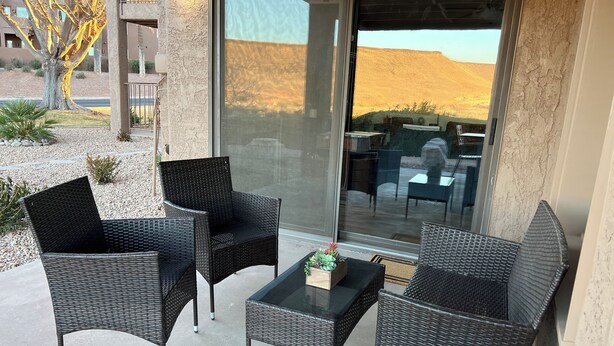 Een balkon met rieten meubilair en een glazen deur naar een terras.