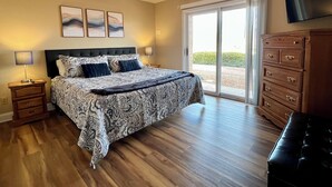 Een slaapkamer met een groot bed, houten nachtkastjes, een dressoir en een tv aan de muur.