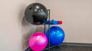 A wall-mounted exercise equipment with a black, pink, and blue exercise ball, and a red and blue resistance band.