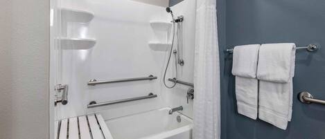 A bathroom with a bathtub, grab bars, a towel rack, and a shower curtain.
