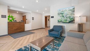 Een moderne lobby met een receptiebalie, een zithoek en een groot schilderij aan de muur.