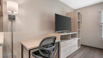 Quarto moderno com televisão de tela plana, escrivaninha, cadeira e prateleiras embutidas.