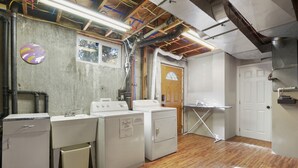 A laundry room with washing machines, a sink, and a drying rack. - The Canon Hill Cottage (Spokane)