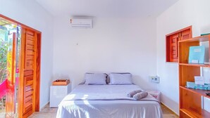 Een slaapkamer met een bed, een houten kledingkast, een airconditioning en een plafondlamp.